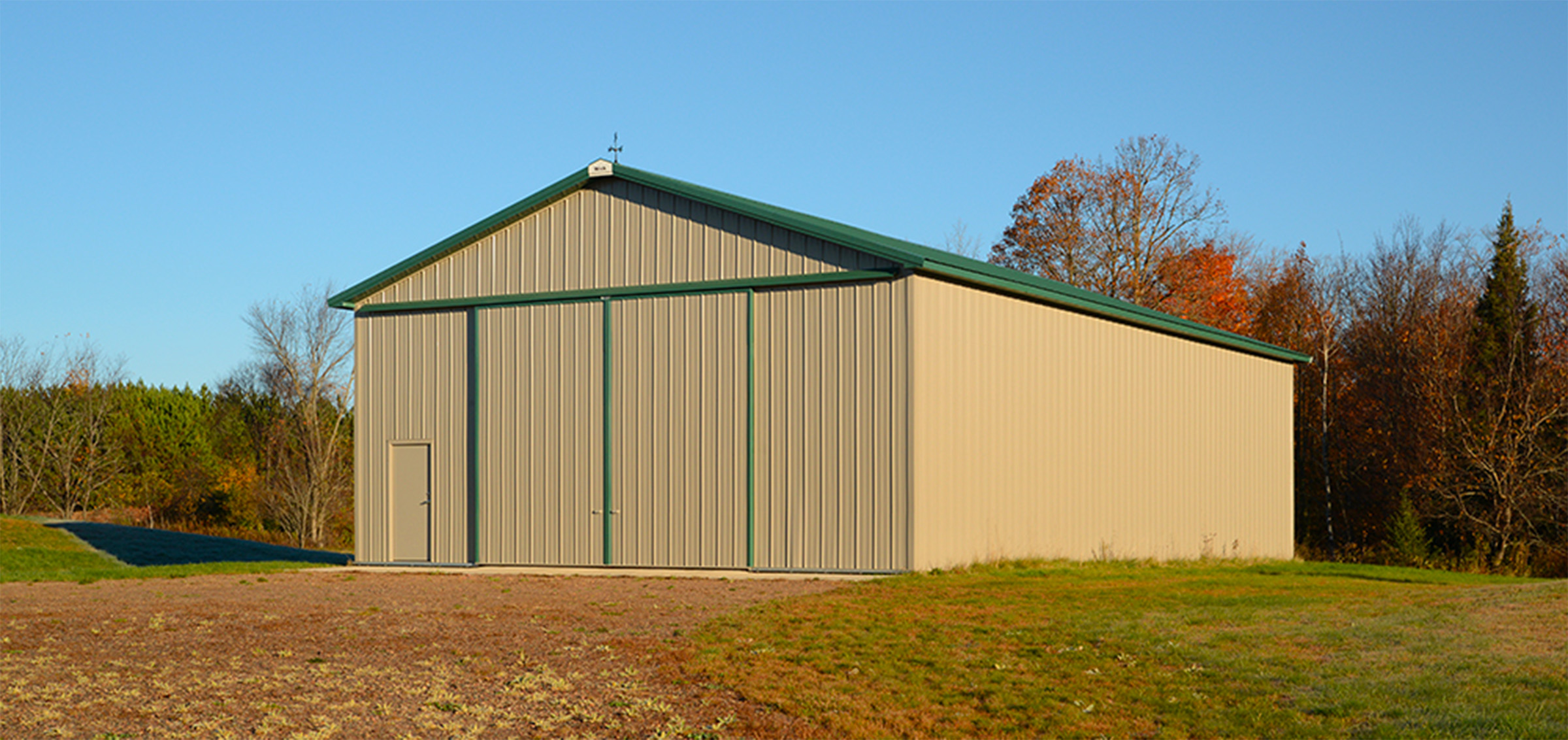 beige and green colored post frame agricultural building